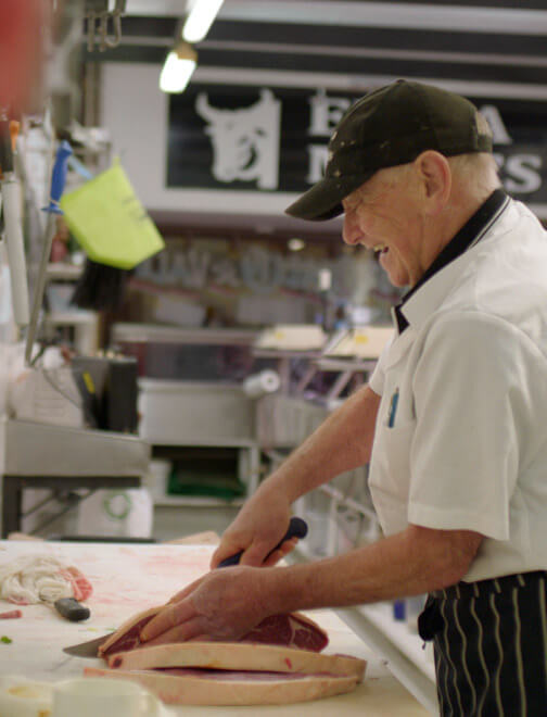 Butcher slicing meat at local butcher.