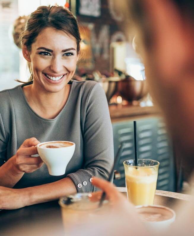 Smiling person holding coffee at cafe.
