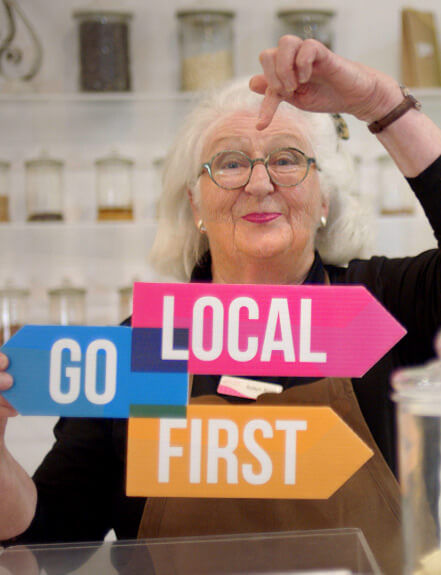 Person holding 'Go local first' sign.