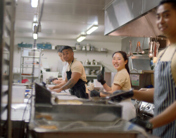 Workers in kitchen smiling.